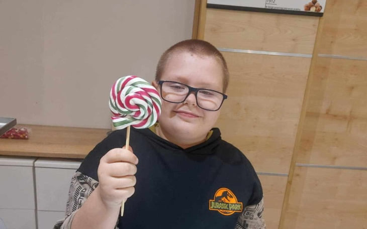 Chłopiec trzymający dużą lizak w kształcie spirali.