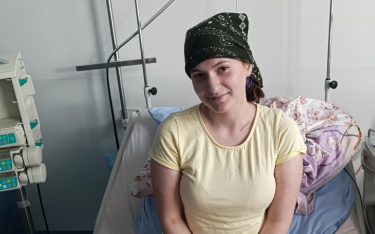 Młoda kobieta w szpitalu, uśmiechająca się w trakcie leczenia.