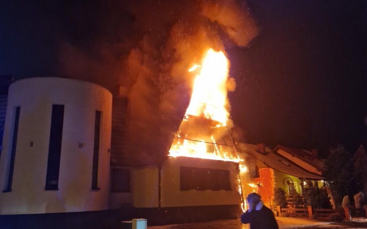 Pożar w budynku, ogień wydobywający się z dachu.