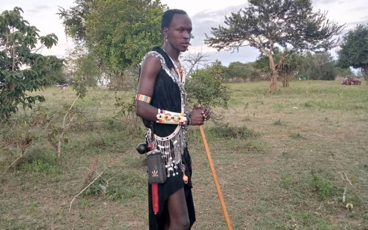 Mężczyzna w tradycyjnym stroju masajskim, trzymający kij.