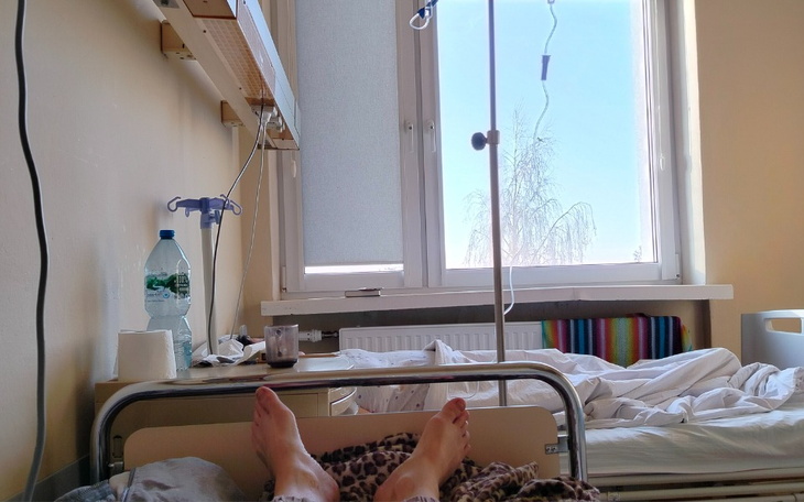 Widok z łóżka szpitalnego, z oknem i pościelą.