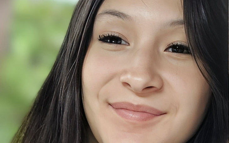 Młoda dziewczyna uśmiechająca się na tle zieleni.