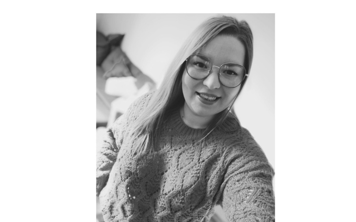 Portret uśmiechniętej kobiety w swetrze, w czarno-białym stylu.