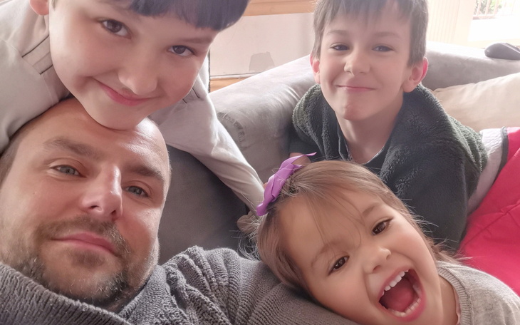 Rodzinne selfie z uśmiechniętymi dziećmi na kanapie.