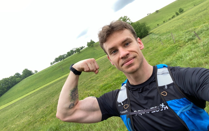 Mężczyzna na tle zielonego krajobrazu, pokazujący mięsień.