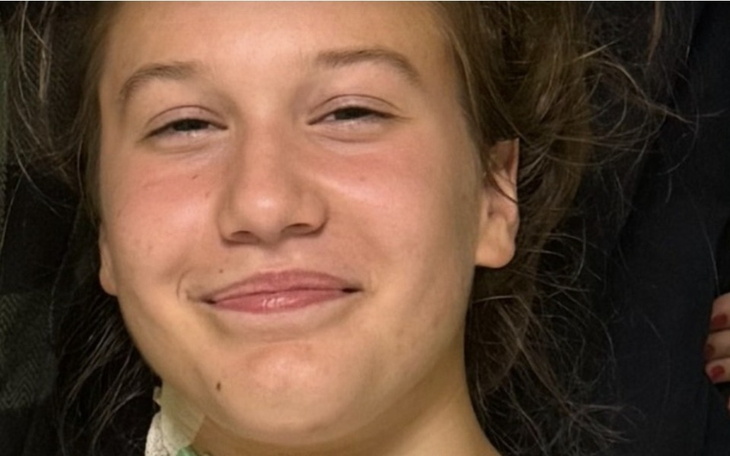 Uśmiechnięta dziewczyna leżąca na łóżku.