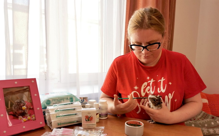 Kobieta opiekująca się małym zwierzęciem, podająca mu lekarstwa.