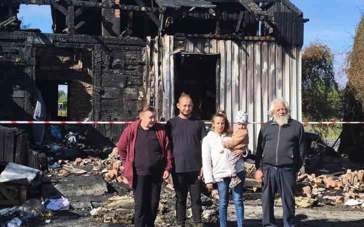 Rodzina przed zniszczonym domem po pożarze.