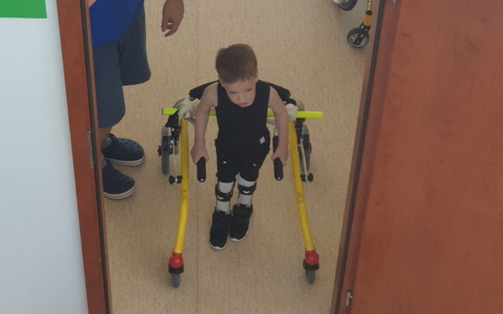 Chłopiec w wózku, korzystający z pomocy w chodzeniu.
