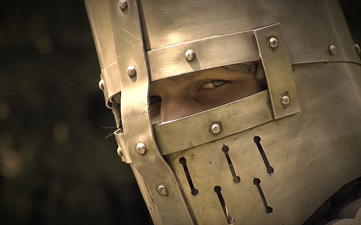 Rycerz w zbroi, gotowy do walki, z intensywnym spojrzeniem.