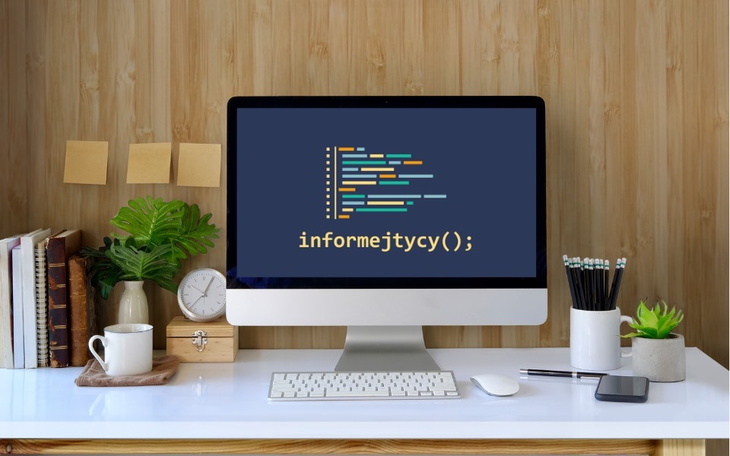 Biurko z komputerem, rośliną i przyborami biurowymi.