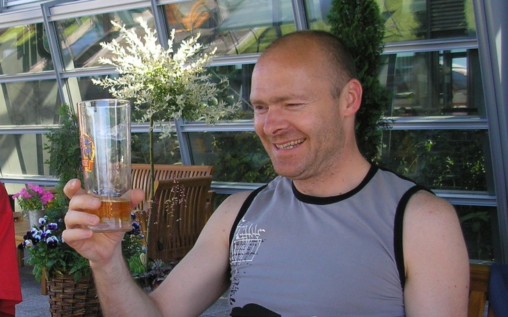 Mężczyzna trzymający szklankę piwa, uśmiechający się.