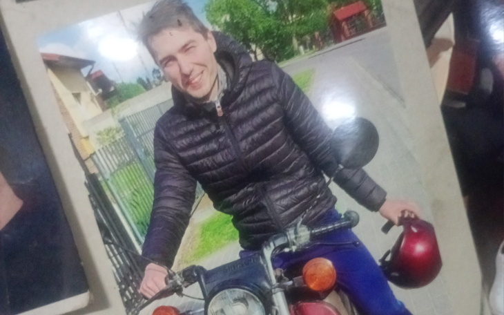 Mężczyzna na motocyklu z kaskiem w ręku.