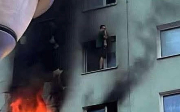 Mężczyzna w oknie podczas pożaru budynku.