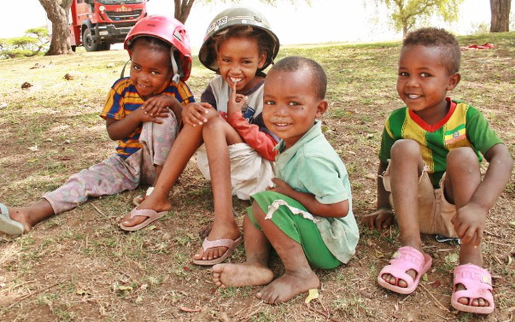 Czwórka dzieci bawiących się na trawie, uśmiechniętych i radosnych.
