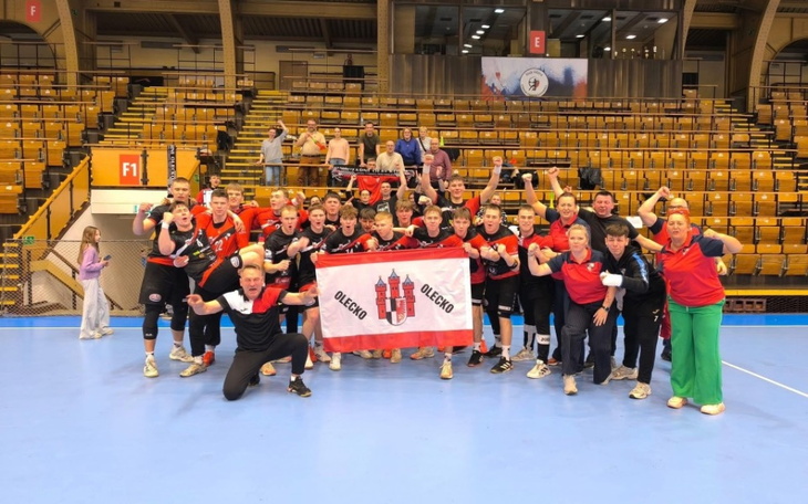 Zespół sportowy z flagą OLECKO na boisku.