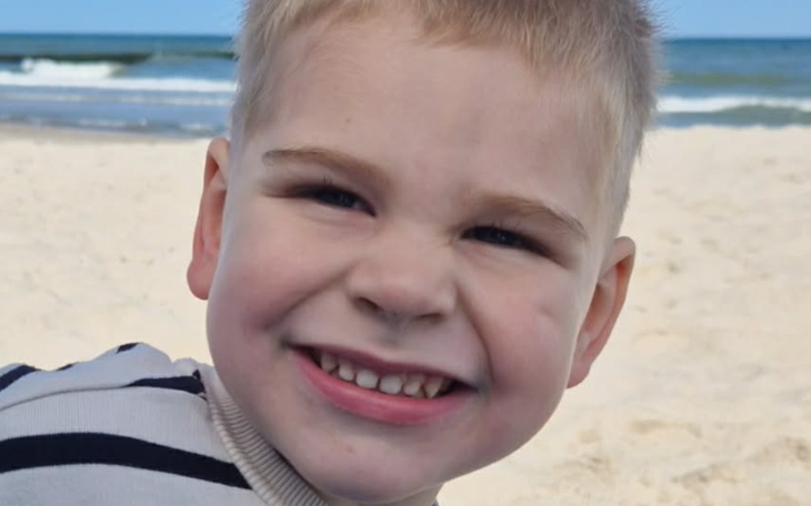 Uśmiechnięty chłopiec na plaży, cieszy się słońcem.