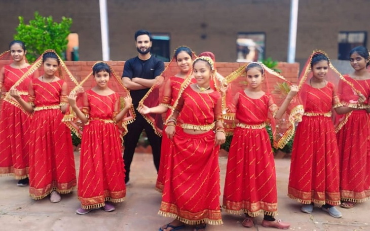 Grupa dzieci w tradycyjnych strojach tańczących w radosnej atmosferze.