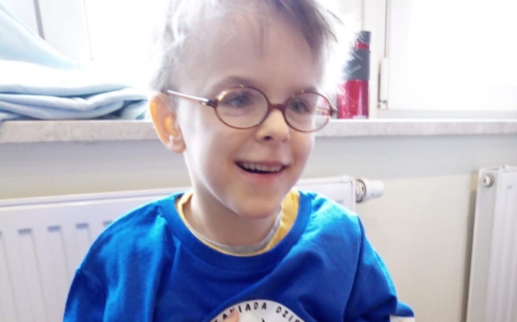 Chłopiec w okularach, uśmiechający się do kamery.