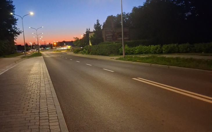 Pusty widok na ulicę o zmierzchu, z delikatnym światłem w tle.