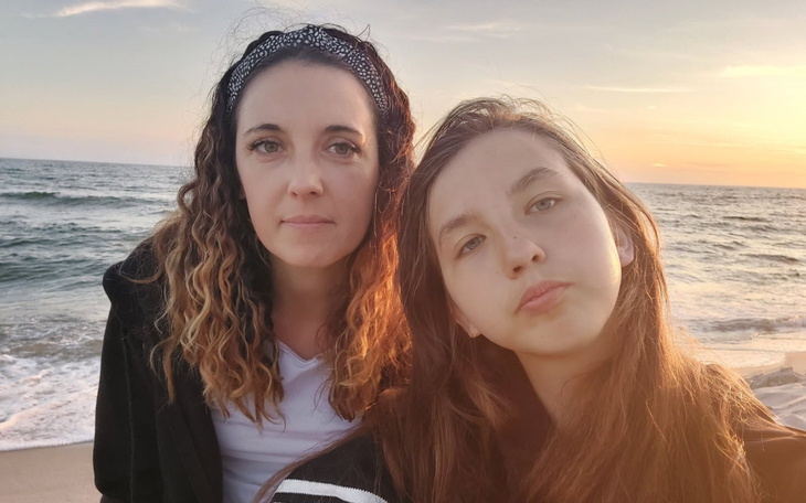 Matka z córką na plaży, w tle zachód słońca.