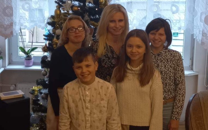 Grupa ludzi pozująca przed choinką w świątecznym otoczeniu.