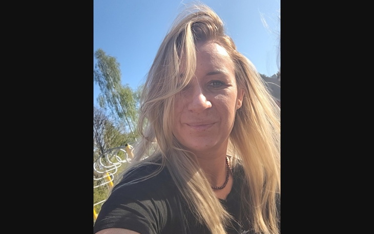 Kobieta z długimi włosami, uśmiechająca się do kamery.