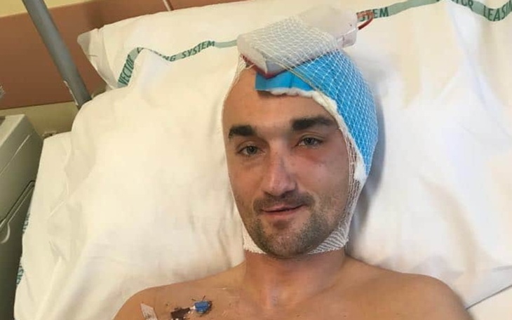 Mężczyzna w szpitalu z opatrunkiem na głowie.