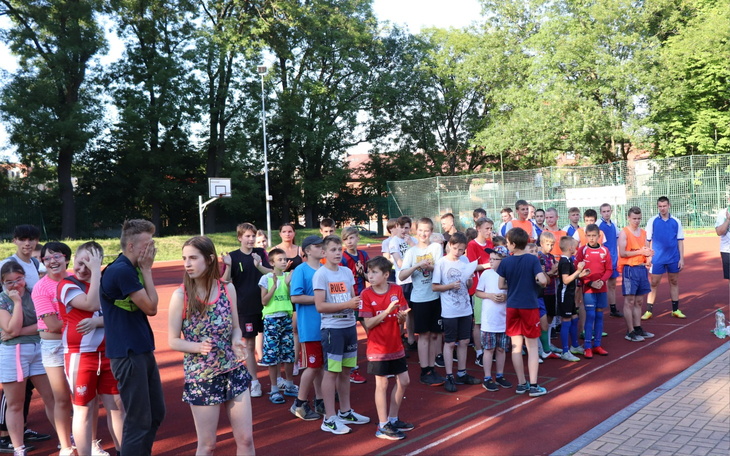 Grupa dzieci na boisku sportowym, gotowych do rywalizacji.