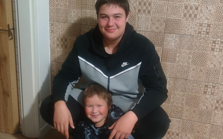 Dwóch chłopców pozujących razem w domu, uśmiechnięci.