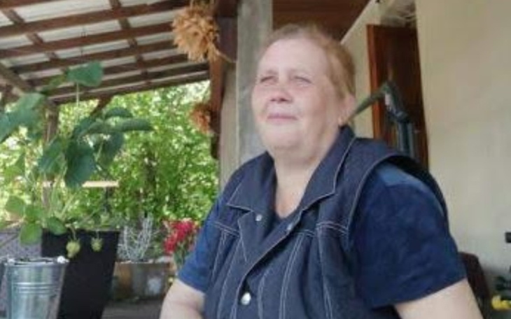 Kobieta w ogrodzie, uśmiechająca się do kamery.