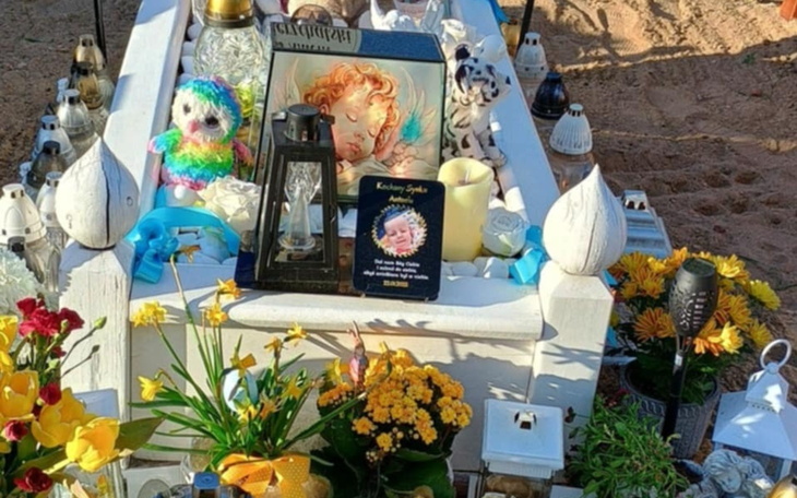 Miejsce pamięci z kwiatami i świecami na grobie.