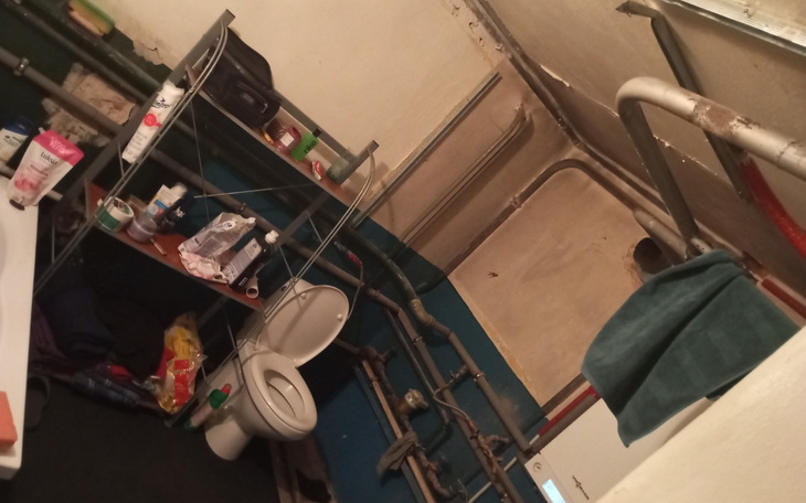 Widok na małą łazienkę z toaletą i półkami.