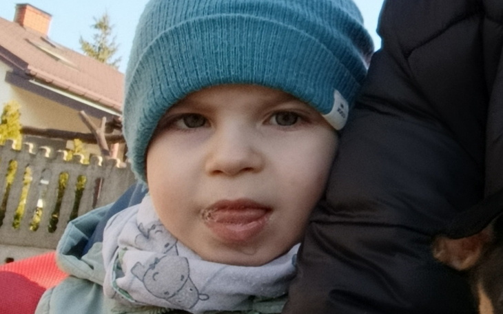 Mały chłopiec w czapce, wystawiający język.