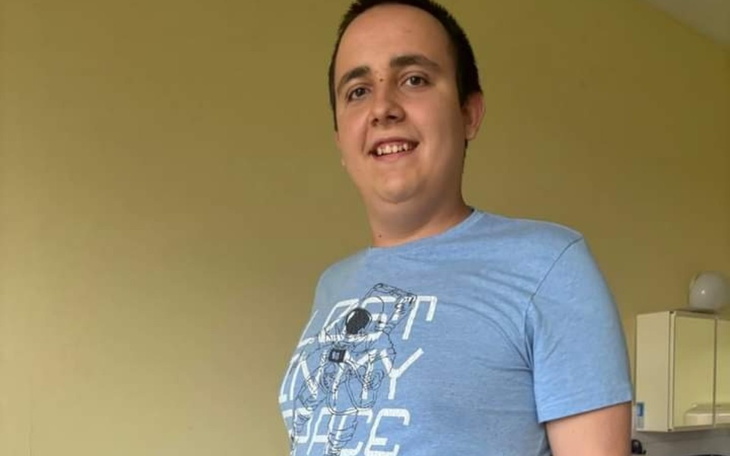 Młody mężczyzna w niebieskiej koszulce, uśmiechający się.