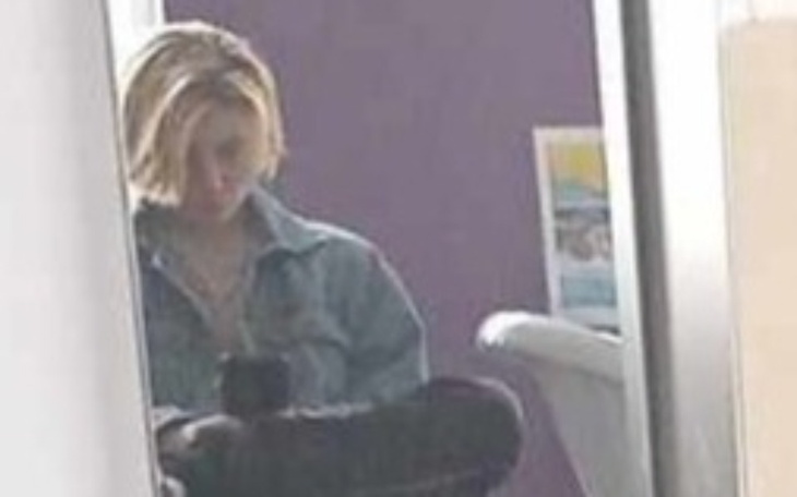 Osoba w lustrze, siedząca na krześle, z krótkimi włosami.