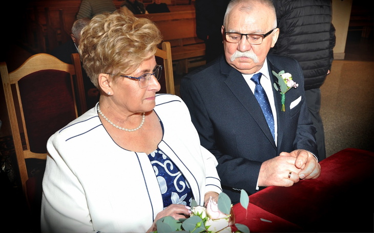 Para starszych ludzi w eleganckich strojach, siedzących razem.