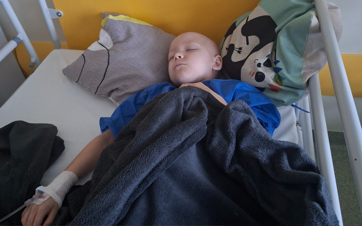 Chłopiec śpiący w szpitalnym łóżku z kroplówką.