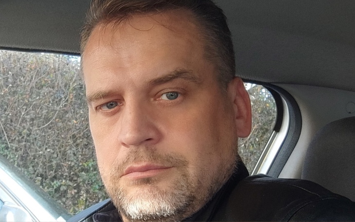 Mężczyzna w samochodzie, z poważnym wyrazem twarzy.