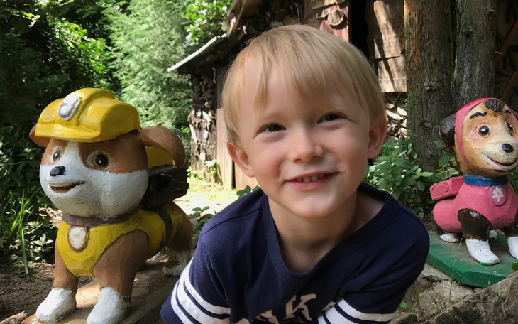 Chłopiec uśmiechający się obok rzeźbionych postaci psów.