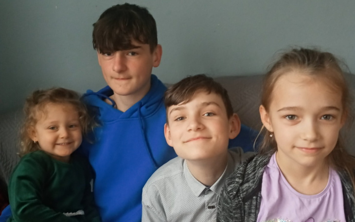 Czwórka dzieci pozująca do zdjęcia w przytulnym wnętrzu.