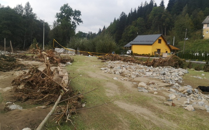 Zniszczony teren po powodzi, z widokiem na dom.