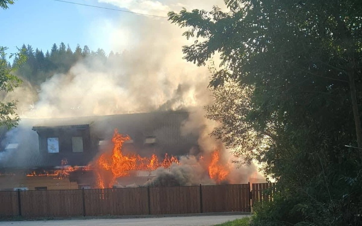Pożar budynku otoczonego drzewami, dym i ogień.