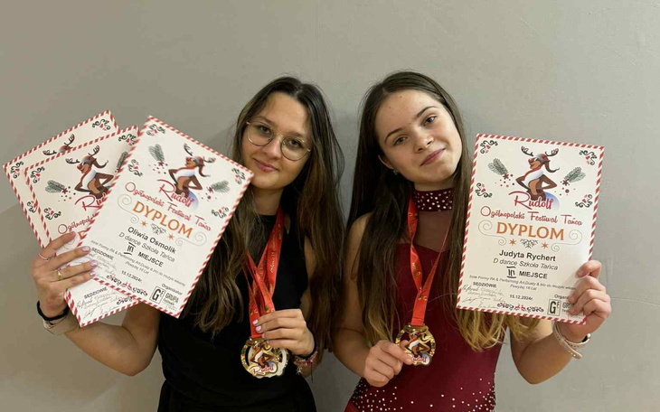 Dwie dziewczyny z dyplomami i medalami, uśmiechnięte po konkursie.