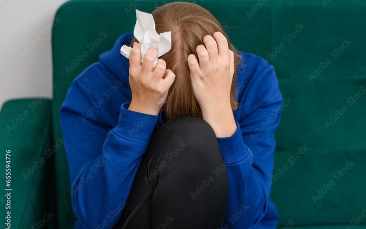 Osoba z ręcznikiem na głowie, siedząca na kanapie.