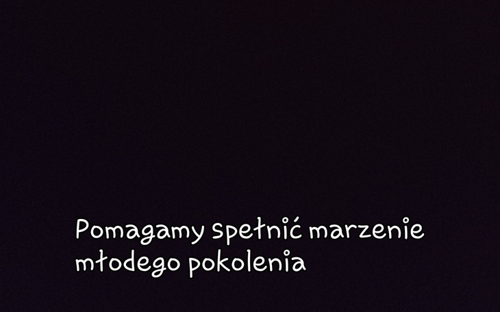 Ciemny kocur leżący na szarym kocu, zrelaksowany.