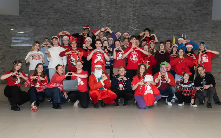 Grupa ludzi w świątecznych strojach, robiących serca z rąk.