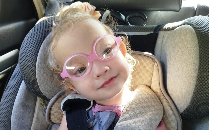 Mała dziewczynka w okularach, uśmiechająca się w samochodzie.