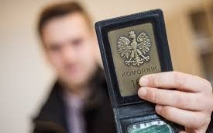 Osoba trzymająca legitymację komornika z orłem.