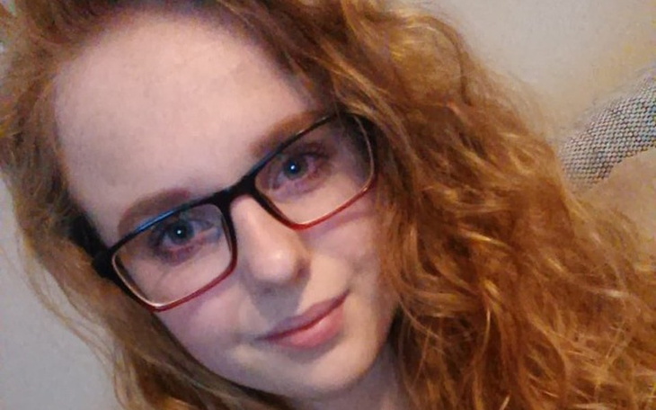 Portret młodej kobiety w okularach, uśmiechnięta.